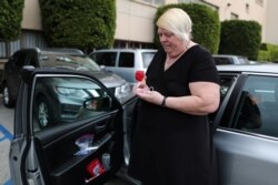 Uber and Lyft driver Tammie Jean Lane, who had part of her lung removed after lung cancer, holds a bottle of hand sanitizer in Los Angeles, California, March 16, 2020.