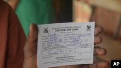 FILE— A man holds a vaccination card that proves he has received the yellow fever vaccine, at Kiswa Health Center III in Kampala, Uganda, April 2, 2024.