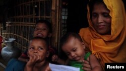 Sait Banu sits at her bamboo shelter with her children at a Rohingya refugee camp in Cox's Bazar, Bangladesh, holding a letter she received from her husband imprisoned in Myanmar, June 28, 2018. 