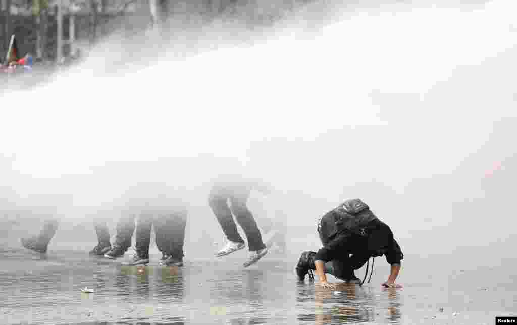 Student protesters are hit by a jet of water released from a riot police water cannon during a demonstration against the government to demand changes in the public state education system in Santiago, Chile, Sept. 5, 2013.