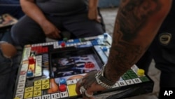 FILE - A player moves his piece in poleana, a board game invented in prison, during a tournament in Mexico City, Nov. 17, 2024. 