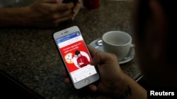 A cellphone user looks at a Facebook page at a shop in Latha street, Yangon, Myanmar, Aug. 8, 2018