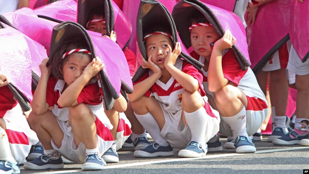 Anak-anak Taiwan berlindung dari sinar matahari dalam latihan perayaan Hari Nasional (8/10) di Taipei. 