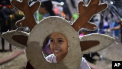 A girl poses for a photo with Christmas decorations in Valencia, Venezuela, Oct. 1, 2024. President Nicolas Maduro declared the Christmas season would start earlier this year in the South American country. 