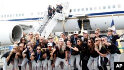 Members of the United States women's soccer team, winners of a fourth Women's World Cup, pose with the trophy after arriving at Newark Liberty International Airport, July 8, 2019, in Newark, New Jersey.