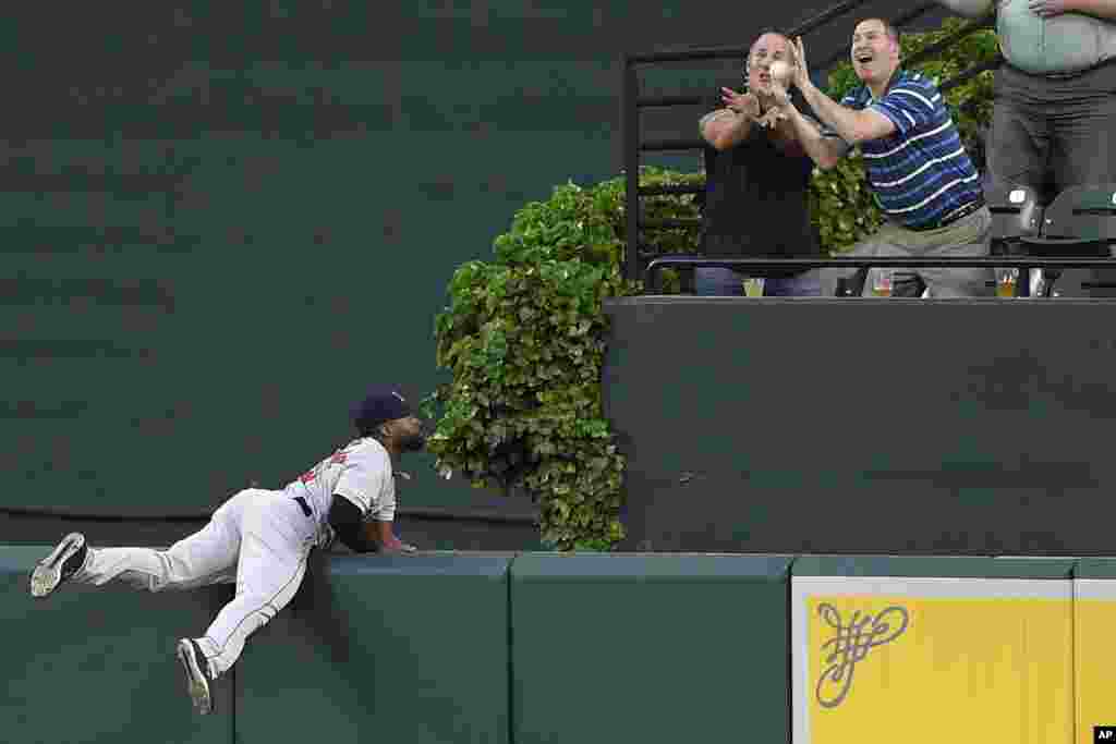 Boston Red Sox player Jackie Bradley Jr., left, watches fans go for a ball hit by Baltimore Orioles&#39; Jonathan Villar in a baseball game, May 6, 2019, in Baltimore, Maryland.