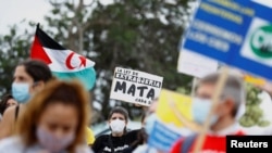 People take part in a demonstration in favor of the rights of migrants, in Arguineguin, Spain, Nov. 14, 2020. The banner reads: "The immigration law kills every day."