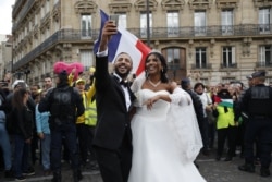 Newlyweds take selfies next to "yellow vest" protesters during an anti-government "yellow vests" (gilets jaunes) protest in Paris, Sept. 28, 2019.