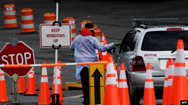 Seorang petugas kesehatan tampak mengatur mobil yang masuk ke lokasi tes COVID-19 di Arlington, Virginia, pada 1 Desember 2020. (Foto: AFP/Olivier Douliery)