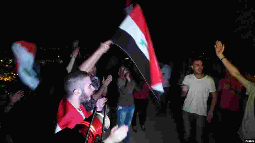 Demonstran pro-Assad melambaikan bendera dan meneriakkan slogan-slogan di Gunung Qasioun, Damaskus, Minggu (1/9).