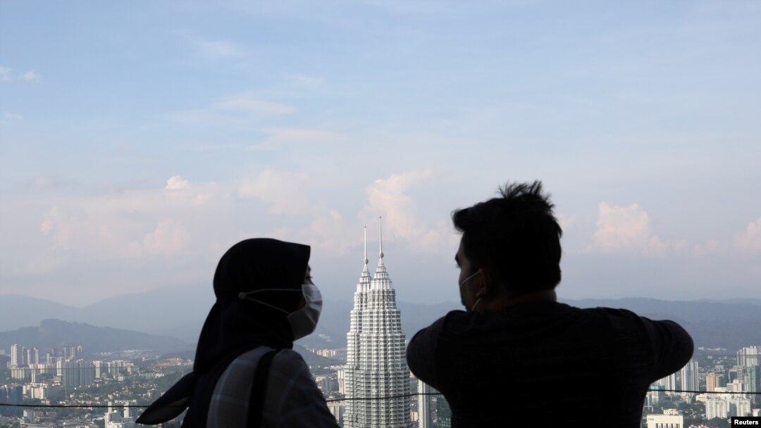 FILE - A couple wearing protective face masks speaks to each other at Kuala Lumpur Tower, amid the coronavirus disease (COVID-19) outbreak, in Kuala Lumpur, Malaysia, July 2, 2020. 