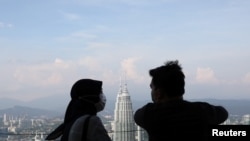 FILE - A couple wearing protective face masks speaks to each other at Kuala Lumpur Tower, amid the coronavirus disease (COVID-19) outbreak, in Kuala Lumpur, Malaysia, July 2, 2020. 