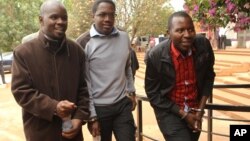 Zimbabwean journalists Brian Chitemba, left, Mabasa Sasa, center, and Tinashe Farawo walk in handcuffs, outside the magistrates courts in Harare, Zimbabwe, Nov. 4.2015.