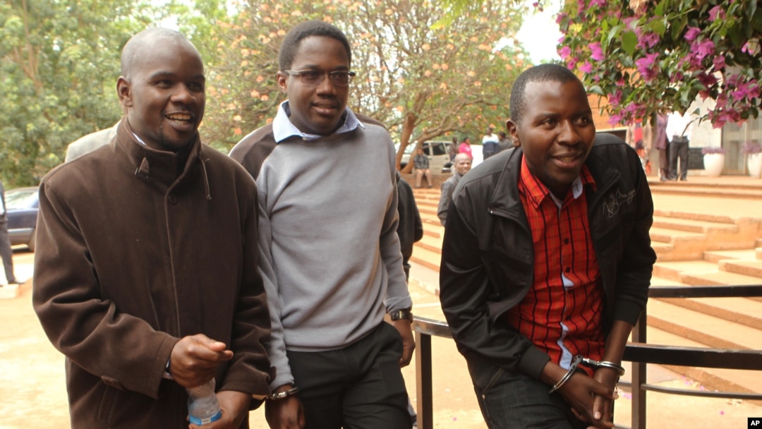 Zimbabwean journalists Brian Chitemba, left, Mabasa Sasa, center, and Tinashe Farawo walk in handcuffs, outside the magistrates courts in Harare, Zimbabwe, Nov. 4.2015.