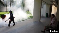 A resident covers his nose as a pest control officer fumigates the Aljunied Crescent cluster in Singapore, Sept. 3, 2016, in this photo taken by Antara Foto. 