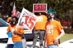 FILE - Activists rally in support of a $15 an hour minimum wage, in Orlando, Florida, Feb. 16, 2021.
