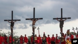 FILE— Ruben Enaje, center, remains on the cross flanked by two other devotees during the reenactment of Jesus Christ's sufferings as part of Good Friday rituals in San Pedro Cutud, north of Manila, Philippines, Friday, March 29, 2024.