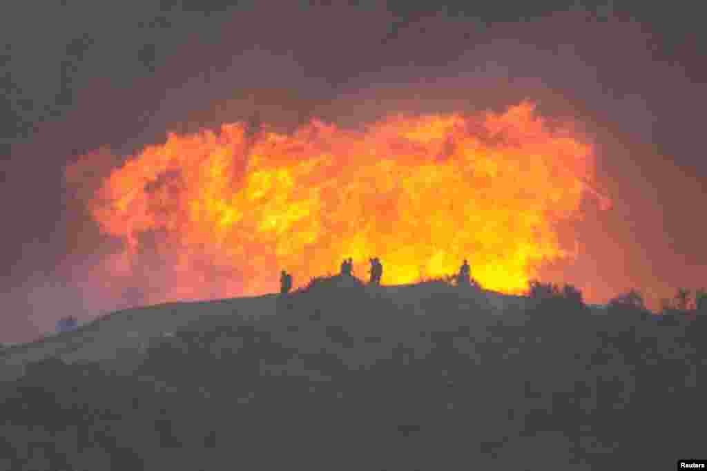 Firefighters battle the Palisades Fire, one of simultaneous blazes that have ripped across Los Angeles County, as seen from the Tarzana neighborhood of Los Angeles, California, Jan. 11, 2025. 