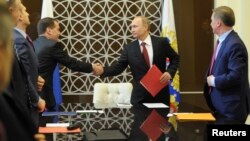 Russian President Vladimir Putin shakes hands with Prime Minister Dmitry Medvedev during a Security Council meeting in Sochi March 13, 2014