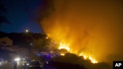 Firefighters work to control a forest fire on a hillside near the village of Ortale, Corsica island, France, July 24, 2015.