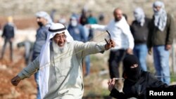 Seorang pria lansia Palestina menggunakan ketapel, ikut bergabung dalam aksi protes terhadap pembangunan permukiman Yahudi di Deir Jarir di Tepi Barat, wilayah Palestina yang diduduki Israel hari Jumat (1/1). 