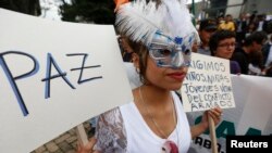 FILE - A demonstrator holds a sign reading "Peace" during a march in Bogota, Nov. 19, 2014.