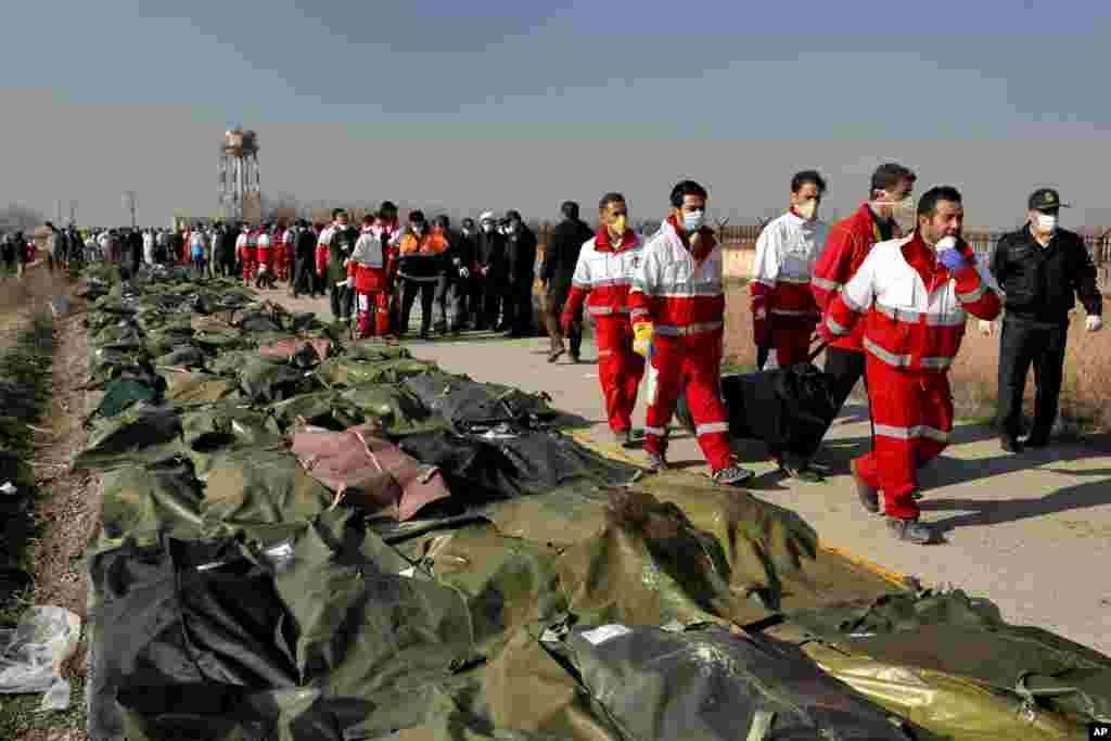 Rescue workers carry the body of a victim of a Ukrainian plane crash in Shahedshahr, southwest of Tehran, Iran, Jan. 8, 2020. The passenger jet carrying 176 people crashed, just minutes after taking off from Tehran&#39;s main airport, killing all on board.