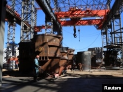 FILE - A person works at Tsingshan's Dinson Iron and Steel Company production plant in Manhize village in Mvuma, Zimbabwe, June 20, 2024