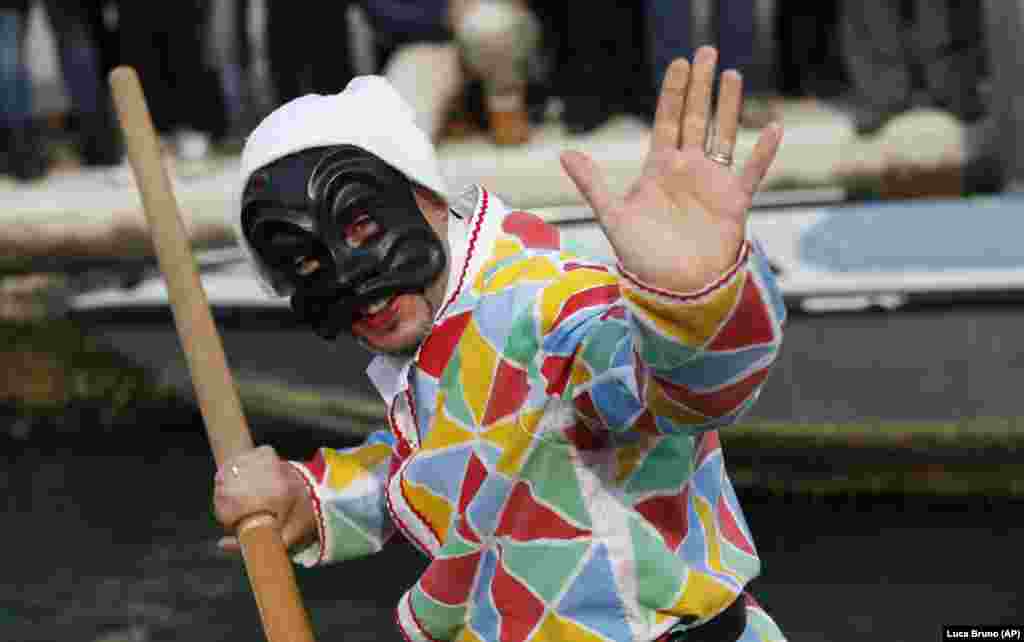 A gondola captain dressed as a harlequin during the famous boat parade through the canals of Venice, Italy.