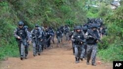 ARCHIVO - Esta fotografía publicada por la Policía Nacional de Ecuador muestra a policías armados llegando para allanar una mina de oro ilegal en Buenos Aires, Ecuador, el 2 de julio de 2019. Bajo el régimen de excepción en el país policías y militares realizan taréas conjuntas.