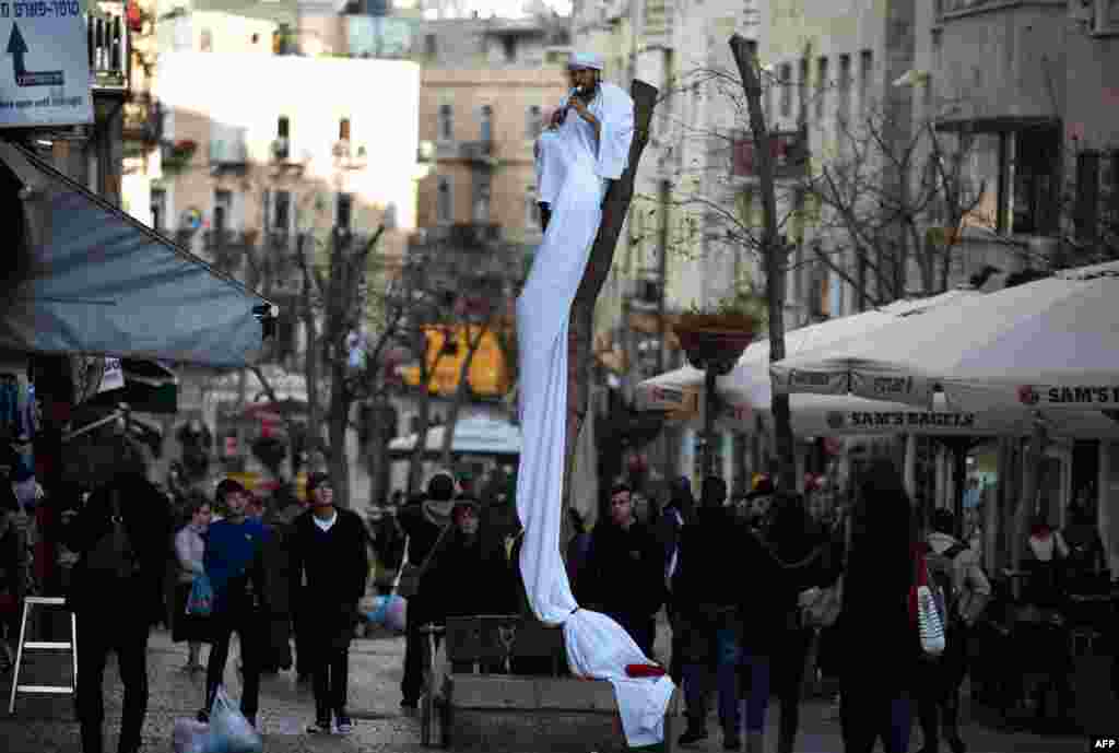 A street musician plays the flute as he sits on top of a tree in the central pedestrian Ben Yehuda street in Jerusalem.