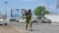 FILE - An armed Somali soldier runs to fight during an attack on Somalia's parliament in Mogadishu, May 24, 2014.