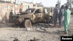 Residents look at an Army vehicle which was damaged during battle between Afghan security forces and Taliban in Farah province, Afghanistan, May 16, 2018. 