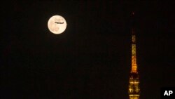 FILE - An airplane flies past the moon rising over Tokyo Tower, Nov. 20, 2021, in Tokyo. Japan announced Nov. 29, 2021, it will suspend entry of all foreign visitors from around the world. 