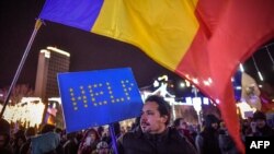 A man holds a cardboard in the colors of the European Union reading 'HELP' as he protests in front of the Romanian Government headquarters in Bucharest, Dec. 10, 2017. 