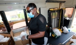Amid concerns of the spread of COVID-19, school lunch worker Brenda Alexander wears a mask as she prepares to distribute meals at an apartment complex in Dallas, Texas, May 5, 2020.
