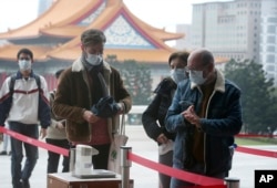 People wear face masks to protect against the spread of the new coronavirus as they visit the Chiang Kai-shek Memorial Hall in Taipei, Taiwan, Thursday, Feb. 27, 2020.