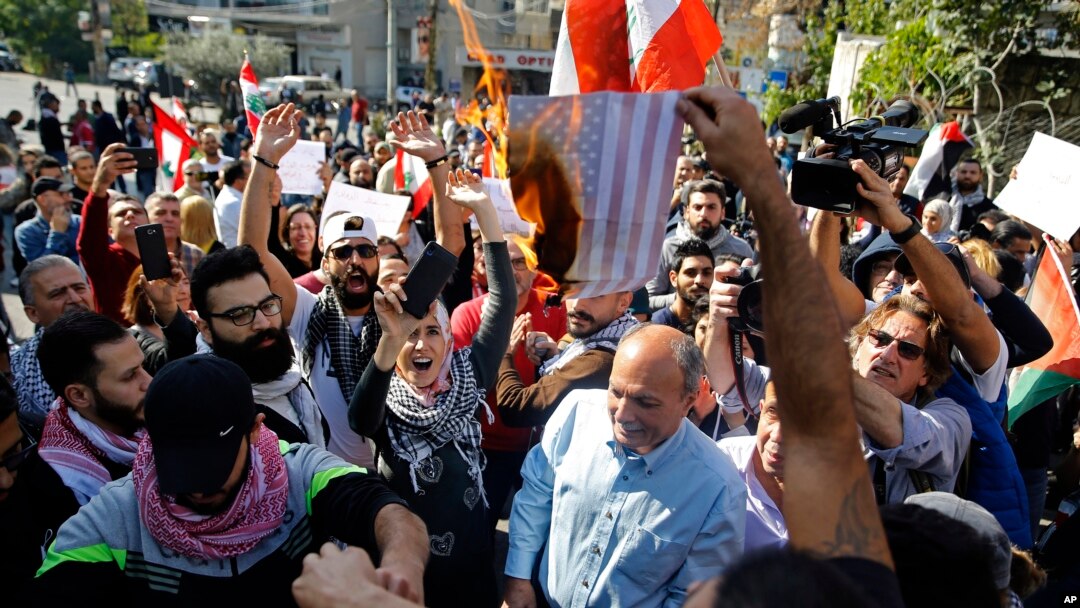 Protesters burn a representation of an American flag during a rally against what they called America's intervention in Lebanon's affairs, near the U.S. embassy in Aukar, northeast of Beirut, Lebanon, Nov. 24, 2019.