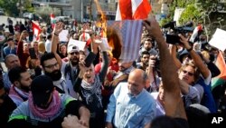 Protesters burn a representation of an American flag during a rally against what they called America's intervention in Lebanon's affairs, near the U.S. embassy in Aukar, northeast of Beirut, Lebanon, Nov. 24, 2019.