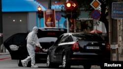 A forensic officer inspects the car of former Greek prime minister and former central bank chief Lucas Papademos following the detonation of an envelope injuring him and his driver, in Athens, Greece, May 25, 2017.