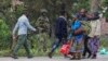 A member of the M23 armed group holds position behind barbed wire as civilians fleeing ongoing clashes in eastern Democratic Republic of Congo cross the border into Rwanda at the La Corniche Border Post in Gisenyi on Jan. 29, 2025. 