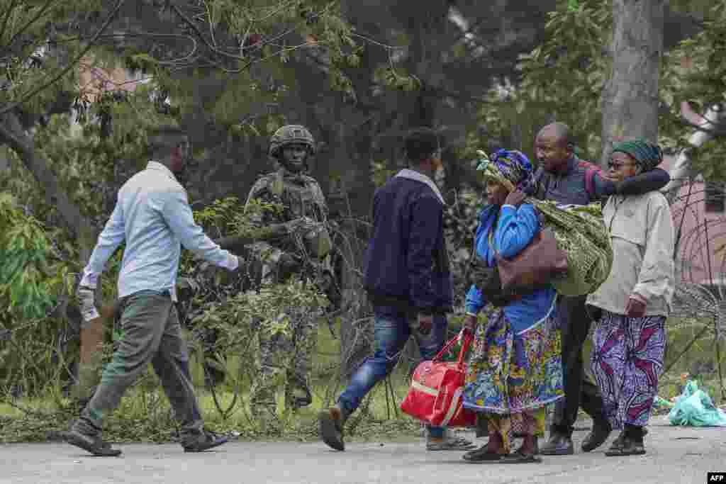 A member of the M23 armed group holds position behind barbed wire as civilians fleeing ongoing clashes in eastern Democratic Republic of Congo cross the border into Rwanda at the La Corniche Border Post in Gisenyi.