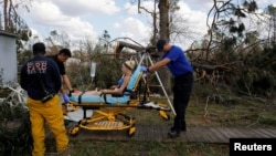 Medics take Angelena Sawyer to the ambulance for her untreated acute appendicitis during a wellbeing check by a 50 Star Search and Rescue team following Hurricane Michael in Fountain, Florida, Oct. 17, 2018.