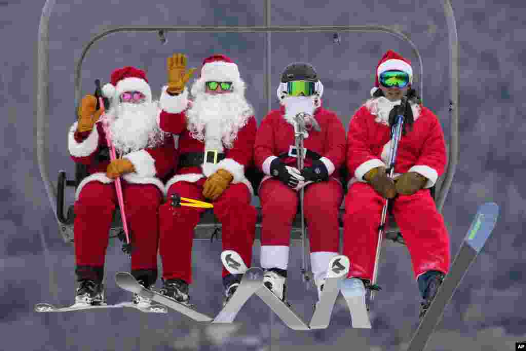 Skiers dressed in Santa Claus outfits ride a chairlift at the Sunday River Ski Resort, Dec. 11, 2022, in Newry, Maine. The skiing Santas raise money for the River Fund, a non-profit organization that supports youth education and recreation in the Bethel, Maine area.&nbsp;