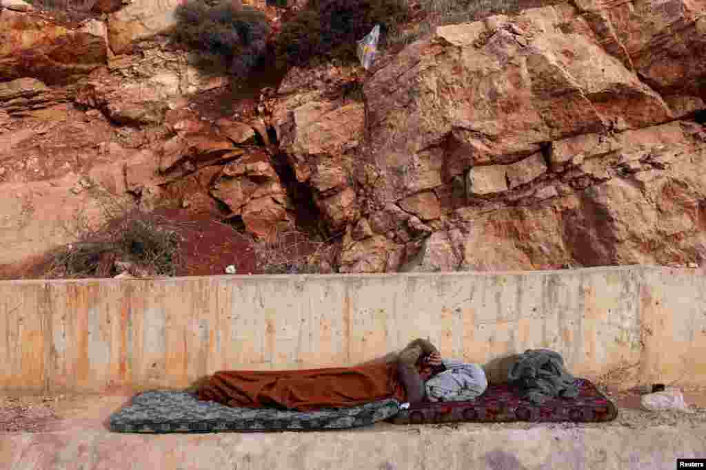 A person lies on a mattress while waiting to cross into Lebanon from Syria, at the Masnaa border crossing, Syria.