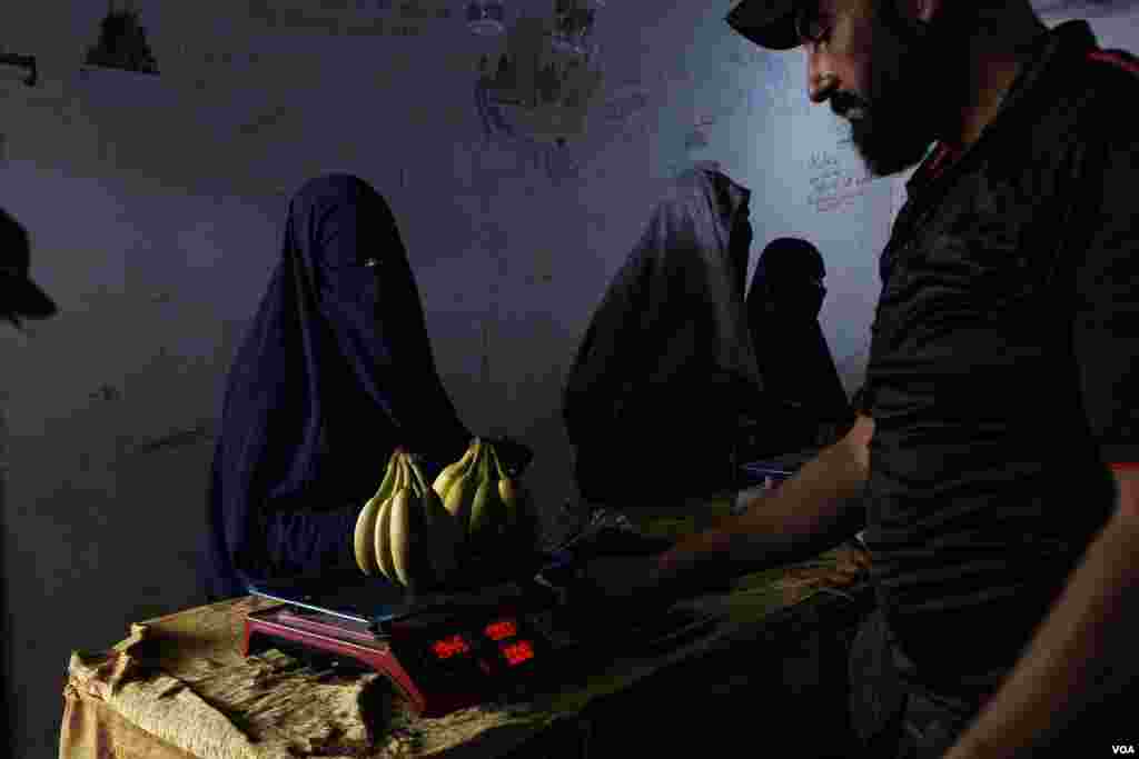 A female prisoner buys fruits in the market area of Roj Camp where most of the western women kept in northeastern Syria have been relocated to the last years, on Oct. 13, 2024 (Diego Baravelli/VOA) 