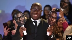 Le réalisateur Steve McQueen pose avec des masques de son propre visage lors de la première de "Widows" au Festival international du film de Toronto au Roy Thomson Hall, le 8 septembre 2018, à Toronto.