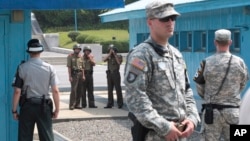 FILE - North Korean army soldiers watch the south side while South Korean, left, and U.S. Army soldiers stand guard at the truce villages of Panmunjom in Paju, South Korea, July 27, 2014.