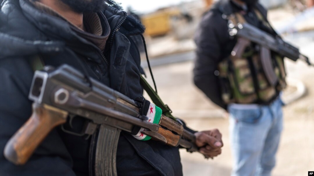 FILE - Members of the new Syrian security forces stand outside a security building, in Nawa, near Daraa, Syria, Jan. 4, 2025.