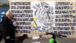 People walk next to a graffiti supporting the release of all hostages who have been held in Gaza since the deadly October 7, 2023 attack, in Tel Aviv